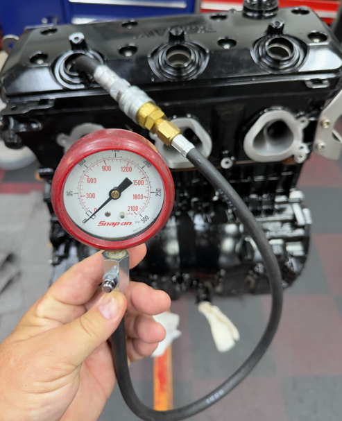 Reading a compression gauge connected to a spark plug hole on a bare PWC engine block