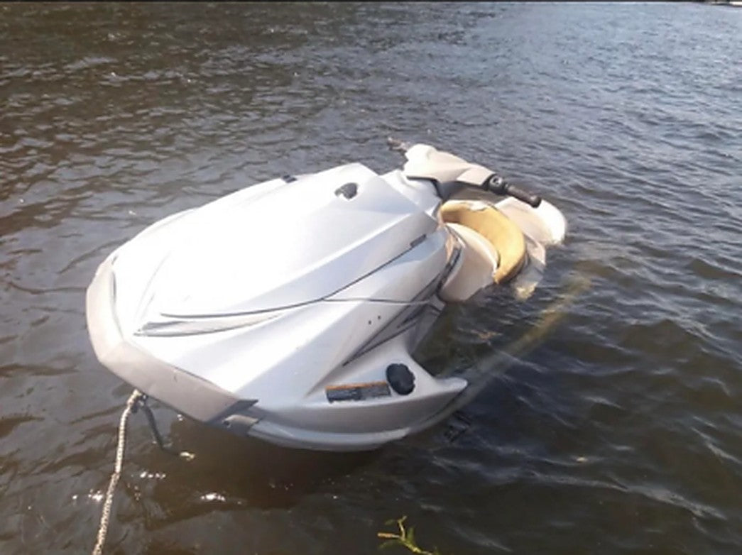Swamped personal watercraft floating low in the water with the hull partly submerged