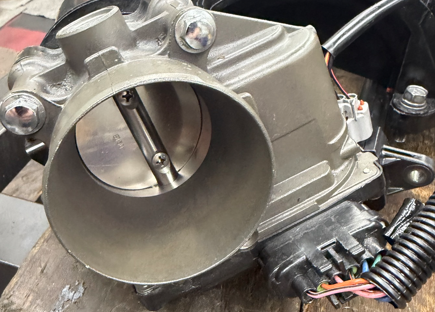 A PWC throttle body showing the butterfly valve bore and throttle position sensor